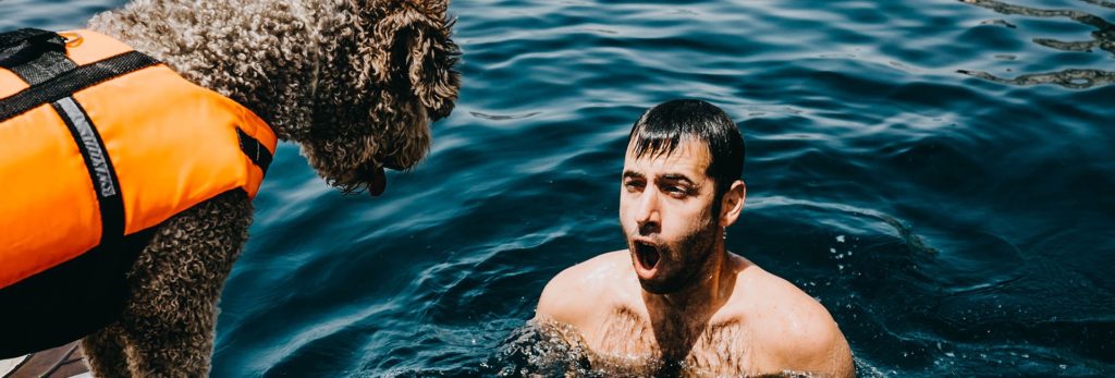 A dog owner captured in the ocean while the dog observes