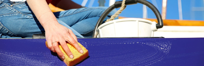 An individual cleaning the exterior of a yacht